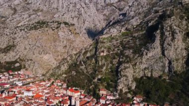 Karadağ 'ın eski ve güzel Avrupa kenti Kotor, körfezdeki dağların eteklerinde, panoramik kuş bakışı, yükseklikten drone atışı.