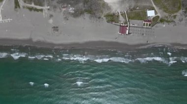Kameralı insansız hava aracı, Adriyatik 'in en yüksek manzaralı, koyu turkuaz dalgalarıyla yıkanan kumlu sahil boyunca yüksekten uçuyor. Sezon dışında ıssız plajlarda tatil köyü.