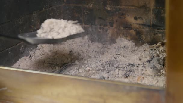 Person removes ash from fireplace with metal shovel at home — Stock Video