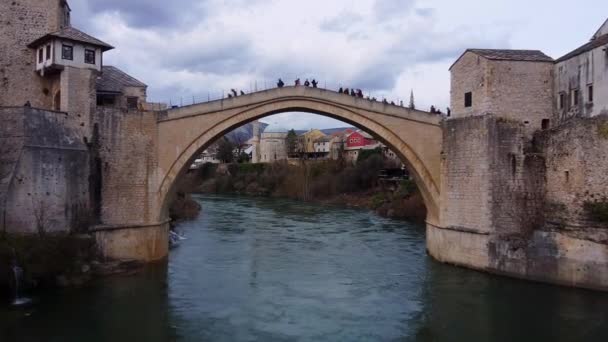 Antike Steinbogenbrücke zwischen den städtischen Ufern mit Menschen — Stockvideo