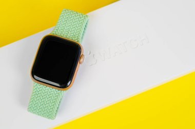 29 Mayıs, Rostov, Rusya: Apple Watch serisi 6, beyaz kutunun sarı arka planına yeşil lastik kayışla bağlandı, kopyalama alanı. Etkin bir yaşam biçimi için akıllı aygıt