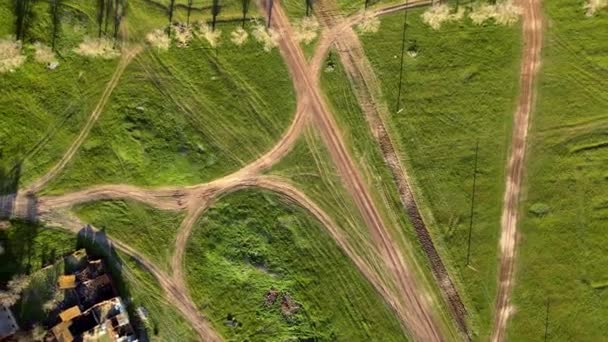 Drone con fotocamera ruota, sollevandosi dal suolo. Campi verdi punteggiati da linee di strade rurali, rara cintura forestale e piccolo villaggio nella valle dalla vista dall'alto — Video Stock