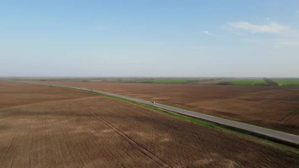Серый длинный шоссе с автомобилями между полями — стоковое видео