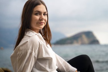 Gülümseyen çekici genç kadın parlak geleceğe bakarken plajda, dağda ve denizde bulanık arka planda poz veriyor. Bayan tatil sırasında deniz kıyısında dinleniyor..