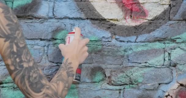 Pintor com tatuagens desenha grafite na parede do edifício de tijolos — Vídeo de Stock