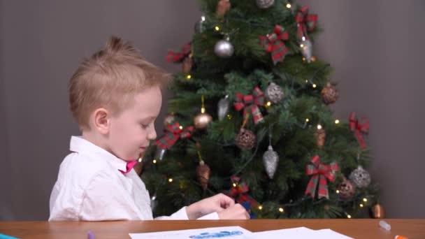 Netter Junge fand Geschenkbox mit Schleife mit Schleife unter dem Weihnachtsbaum dekoriert, er öffnet sie, und im Inneren ist Spielzeug, das er wirklich schon lange wollte. Kind wird von freudigen Emotionen überwältigt — Stockvideo