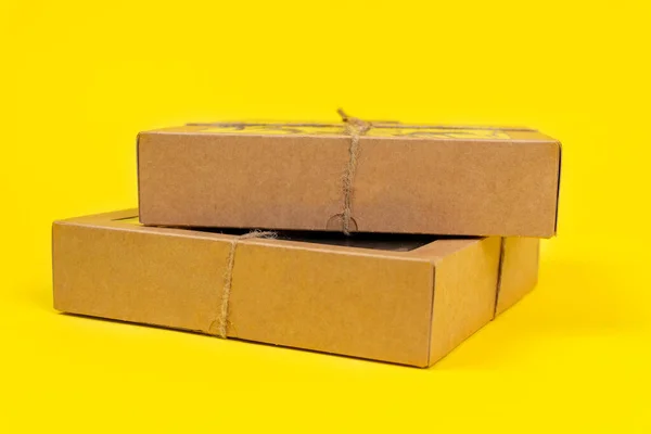 Cajas reciclables de cartón atadas con un cordel ecológico, para almacenamiento y entrega, sobre fondo amarillo, espacio de copia — Foto de Stock