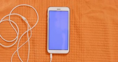 Boş ekranlı telefon ve turuncu kumaşlı kulaklık.