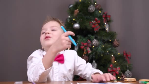 Good boy has behaved well all year, so he writes letter with wishes to Santa to get cool gift and consults with his parents about it, or tells fascinating Christmas story — Stock Video