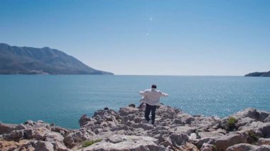 Bir adam zorlu kayalıklardan geçerek kıyıya çıkar, doğanın ve huzurun tadını çıkarır..