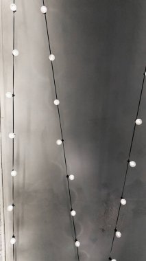 Kalıplı gri bir duvara dayanan sicim ışıklarıyla minimalist estetik. İnce ışıklandırma ve modern tasarım ev dekorasyonu için mükemmel sakin bir atmosfer yaratır..