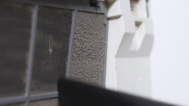Havalandırma filtresinden tozu kaldıran el yapımı vakum hortumunu kapat, fayanslı duvara ve beyaz üniteye yumuşak odaklan, sığ alan derinliğine sahip HVAC temizlik ve bakımını göster