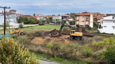Kazıcı ve buldozerli inşaat sahası Yunanistan 'da bir yerleşim bölgesinde vakıf kazıları üzerinde çalışıyor. Ağır makineler yeni bina geliştirme için zemin hazırlıyor.