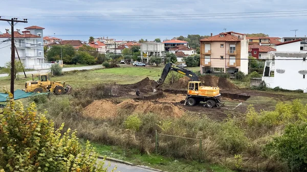 Kazıcı ve buldozerli inşaat sahası Yunanistan 'da bir yerleşim bölgesinde vakıf kazıları üzerinde çalışıyor. Ağır makineler yeni bina geliştirme için zemin hazırlıyor.