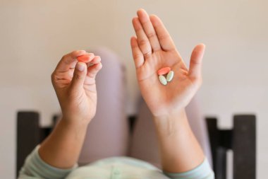 Elinde hapla bir sandalyede oturan bir insanın yakın çekimi. 