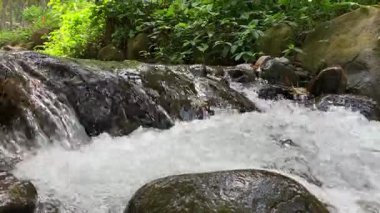 Kayaların arasından akan akarsu. Akan suyla nehir taşlarına yaklaş.
