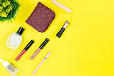 Üst manzara ve düz güzellik seti dekoratif kozmetik ürünleri ve sarı arka planda cüzdan 