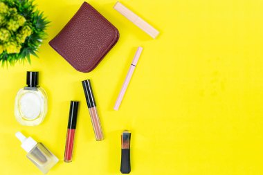 Üst manzara ve düz güzellik seti dekoratif kozmetik ürünleri ve sarı arka planda cüzdan 