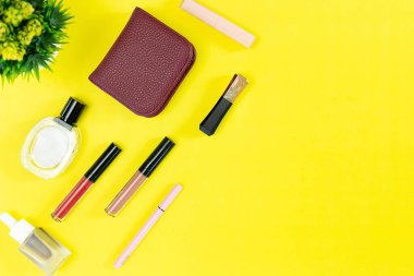 Üst manzara ve düz güzellik seti dekoratif kozmetik ürünleri ve sarı arka planda cüzdan 