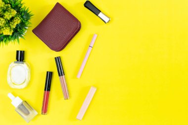 Üst manzara ve düz güzellik seti dekoratif kozmetik ürünleri ve sarı arka planda cüzdan 