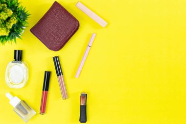Üst manzara ve düz güzellik seti dekoratif kozmetik ürünleri ve sarı arka planda cüzdan 