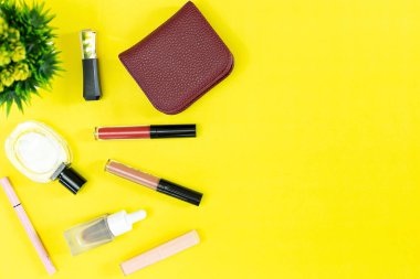 Üst manzara ve düz güzellik seti dekoratif kozmetik ürünleri ve sarı arka planda cüzdan 