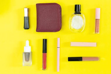 Üst manzara ve düz güzellik seti dekoratif kozmetik ürünleri ve sarı arka planda cüzdan 