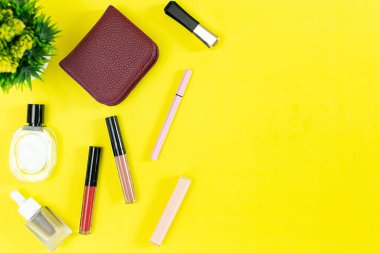 Üst manzara ve düz güzellik seti dekoratif kozmetik ürünleri ve sarı arka planda cüzdan 