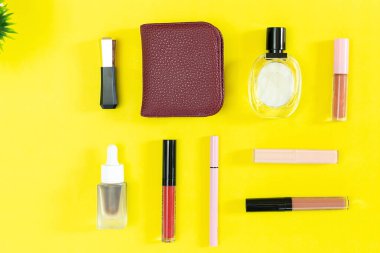 Üst manzara ve düz güzellik seti dekoratif kozmetik ürünleri ve sarı arka planda cüzdan 