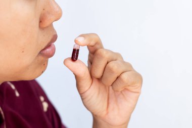 İlaç almak ve sağlık hizmetleri için kapsülü ağzına yakın tutan kişinin yakın plan görüntüsü..