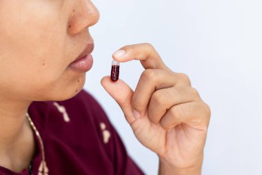 İlaç almak ve sağlık hizmetleri için kapsülü ağzına yakın tutan kişinin yakın plan görüntüsü..