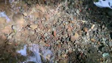 Yansıtıcı berrak su ve güneş ışığının altında kayalar.