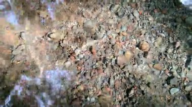 Yansıtıcı berrak su ve güneş ışığının altında kayalar.