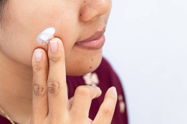 Крупный план женщины Применение крема на щеке с подсказками для кожи Routine.showcasing спокойный момент кожи и повседневной рутины красоты.