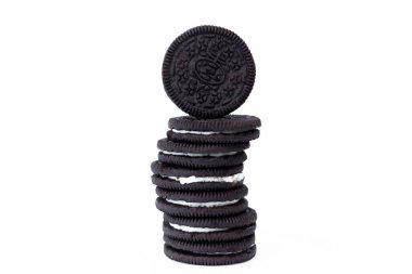 Çikolatalı sandviç kurabiyesinin bir yığın Oreo kurabiyesinin üzerine yakın plan, neşeli bir atıştırmalık anı, tatlı fikri ve beyaz arka planda koyu renkli kurabiyelerle çevrili tatlı ikramları sergileme cazibesi. Atıştırmalıklar ve tatlılar için yiyecek tasvirleri..