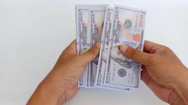 Beyaz arka planda Amerikan dolarlarını sayan bir elin yakın çekimi. Finans, bankacılık, iş ve işlem temaları için elverişli. 