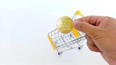 El, modern ekonomide kripto ticaretini, dijital alışverişi ve dijital finansmanı sembolize eden küçük bir alışveriş arabasına sahte Bitcoin yerleştirir..