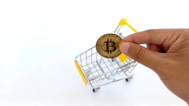El, modern ekonomide kripto ticaretini, dijital alışverişi ve dijital finansmanı sembolize eden küçük bir alışveriş arabasına sahte Bitcoin yerleştirir..