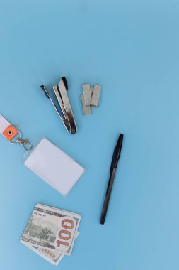 Dikey ofis kağıdı, boş kimlik kartı ve mavi arka planda 100 dolarlık banknot. Yukarıda yeterince kopyalama alanı var. Şirket giderleri, iş bütçesi ve dikey mobil pankart tasarımı kavramı.