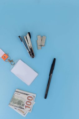 Dikey ofis kağıdı, boş kimlik kartı ve mavi arka planda 100 dolarlık banknot. Yukarıda yeterince kopyalama alanı var. Şirket giderleri, iş bütçesi ve dikey mobil pankart tasarımı kavramı.