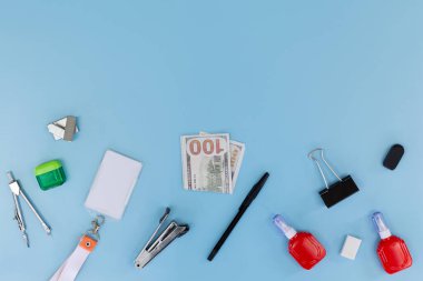 Ofis malzemeleri, boş kimlik kartı ve mavi arka planda 100 dolarlık banknot. İş yeri kimliği kavramı, kurumsal finans, iş harcamaları ve iş için çalışan bütçesi.