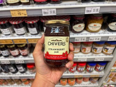 Putrajaya, Malezya - 28 Kasım 2025: Bir el, bir market koridorunda bir kavanoz Chivers Strawberry Jam 'i tutuyor ve ürün etiketini gösteriyor.