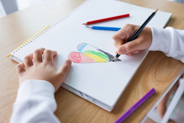 Çocukların kalp şeklini beyaz kağıda renkli kalemlerle boyamaları, yaratıcı çocukların sanat faaliyetleri, evde veya okulda eğitim ve öğrenme, çocukluk yaratıcılığı ve hayal gücü kavramları.