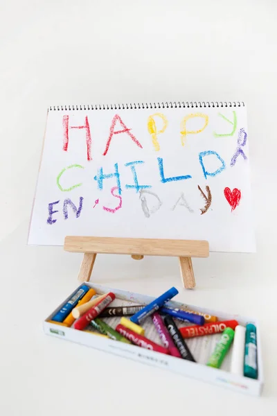 Happy Children Day artwork made with oil pastels displayed on a wooden easel. Colorful kids drawing concept for education, creativity and childhood celebration.