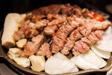 Izgarada otantik Kore barbekü bifteği dramatik ışıklandırma ve buharla geleneksel Asya ızgara yemekleri sergileniyor..