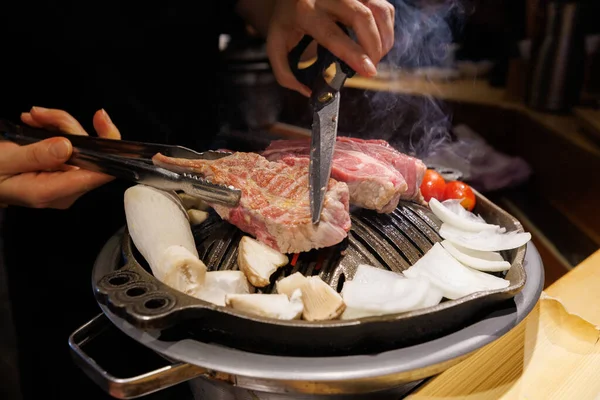Traditional Korean barbecue with sizzling beef meat on tabletop grill, served with onions and mushrooms. Delicious Asian food concept.
