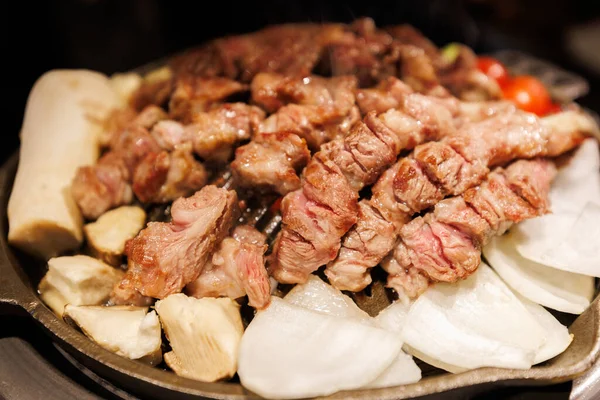 Authentic Korean barbecue beef on grill with dramatic lighting and steam, showcasing traditional Asian grilled food.