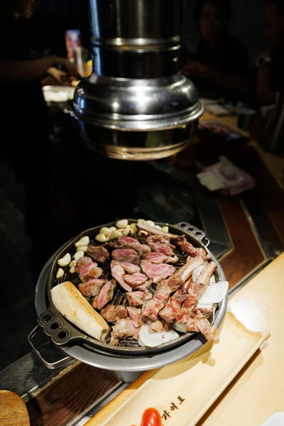 Hot Korean BBQ grill with fresh beef meat cooking in restaurant setting. Asian cuisine, comfort food and dining lifestyle concept.