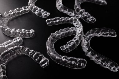 Siyah arkaplana saçılmış plastik ortodonti hizalayıcılarını temizle