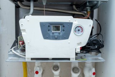 Açık kapaklı modern gaz kazanı, ısıtma sistemi bakımı, merkezi ısıtma ekipmanları, sıcak su kaynağı, ev enerjisi verimliliği, tesisat kurulumu, onarım ve teknik denetim